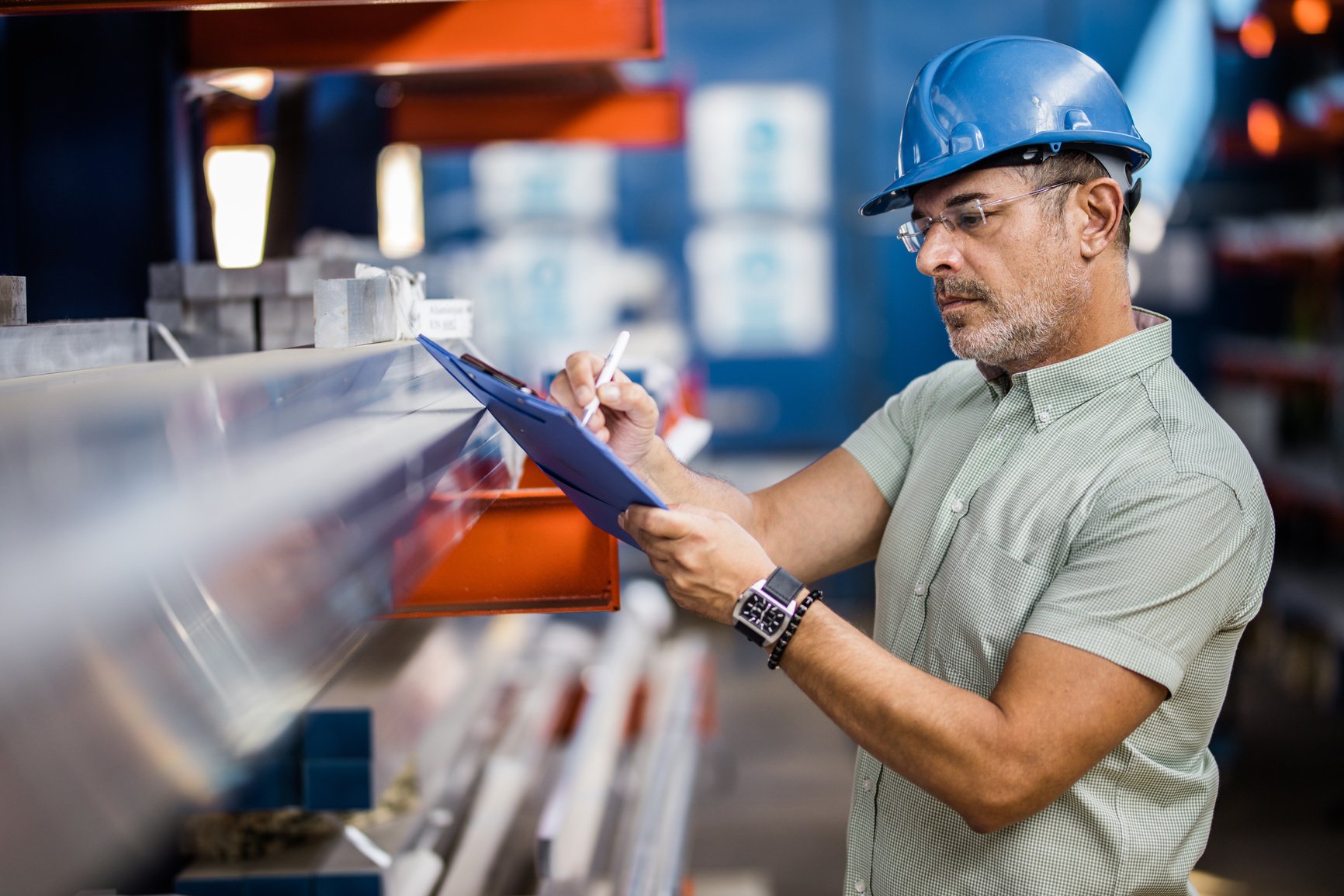 Quality control inspector taking notes in a steel mill.